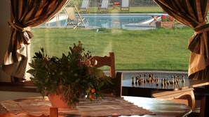 A dining table with a chessboard, a potted plant, and a view of a pool and chairs outside. - Villa in Monticchiello with pool,Airconditioning,BBQ,Garten,Table tennis,sleep14 (Monticchiello)