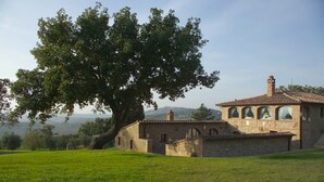 A stone building with a tiled roof, arched windows, and a chimney. - Villa in Monticchiello with pool,Airconditioning,BBQ,Garten,Table tennis,sleep14 (Monticchiello)