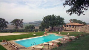 A swimming pool with lounge chairs and a stone building in the background. - Villa in Monticchiello with pool,Airconditioning,BBQ,Garten,Table tennis,sleep14 (Monticchiello)