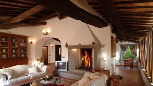 A cozy living room with a fireplace, sofas, and a television. - Villa in Monticchiello with pool,Airconditioning,BBQ,Garten,Table tennis,sleep14 (Monticchiello)