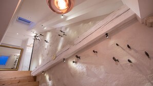 Une pièce avec des poutres apparentes, un grand miroir et un luminaire au plafond.