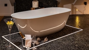 Une salle de bain moderne avec une baignoire sur pieds, un puits de lumière et une vue sur le paysage urbain.
