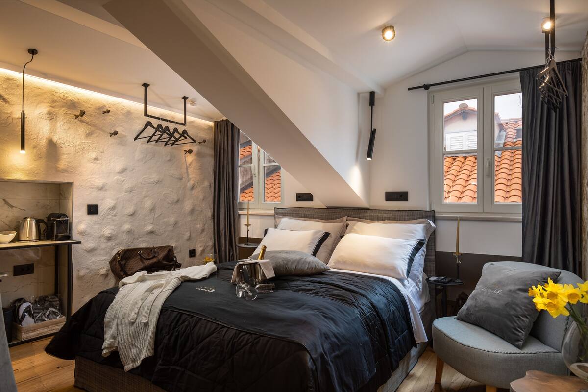 Ein modernes Schlafzimmer mit Bett, Nachttisch und Blick ins Freie durch ein Fenster.