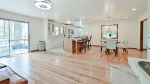 A spacious kitchen with a central island, a dining area with chairs, and a large window providing natural light. - Modern Home Near The Battery Truist Park & Marietta Square Steam Shower Sleeps 8 (Marietta)