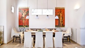 Un coin repas avec une table en bois, des chaises blanches et deux tableaux accrochés au mur.