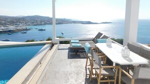 Eine Terrasse mit Pool, mit Blick auf eine Küstenlandschaft, Boote und eine ferne Meeresaussicht.