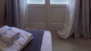 Ein Zimmer mit Bett, einem Vorhangfenster und Blick auf das Meer und die felsige Küstenlandschaft.