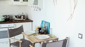 Eine moderne Küche mit weißen Schränken, einem Bambusstuhl und einem Esstisch für vier Personen.