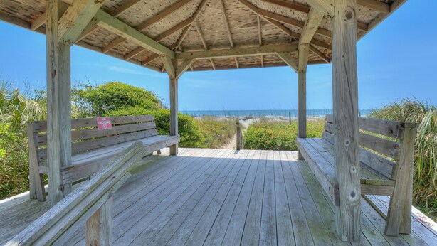 Une terrasse en bois avec des bancs donnant sur une plage.