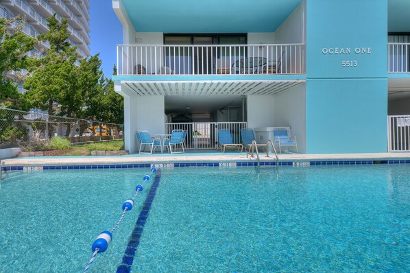A hotel with a pool, a balcony with chairs, and a building number 5513.