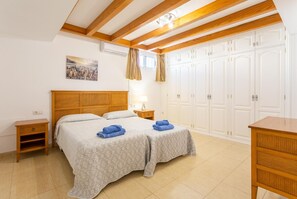 Ein Schlafzimmer mit einem hölzernen Kopfteil, zwei Betten, einem Nachttisch, einem Schreibtisch und einem Kleiderschrank.