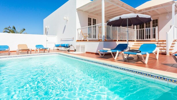 A pool area with lounge chairs and a covered seating area.