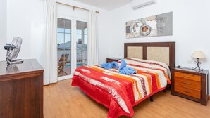 A bedroom with a bed, a desk, a chair, a nightstand, and a ceiling fan.