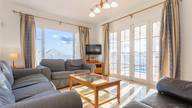 A spacious living room with a sofa set, a coffee table, and a TV.