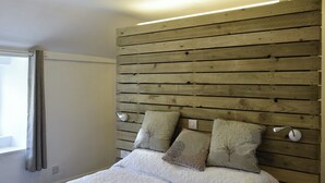 Une chambre à coucher avec une tête de lit en bois, un couvre-lit blanc et deux oreillers.