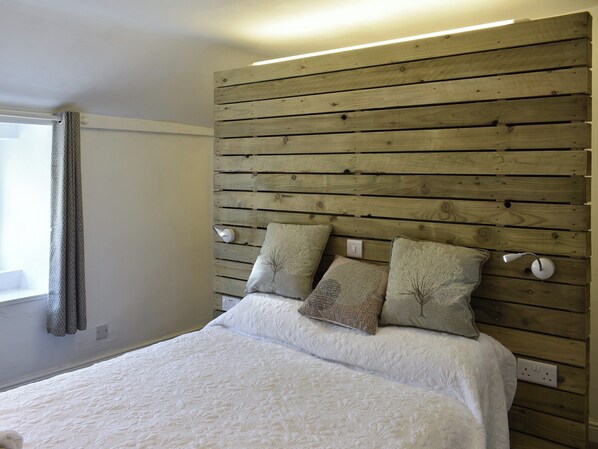 Une chambre à coucher avec une tête de lit en bois, un couvre-lit blanc et deux oreillers.