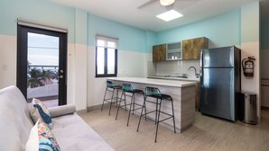 Een moderne keuken met een centraal eiland, barkrukken, een koelkast en een plafondventilator.