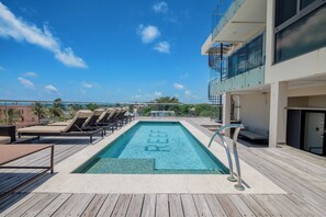 A rooftop pool with lounge chairs and a clear view of the city skyline. - GOLD STANDARD | Sands Suite (San Pedro)