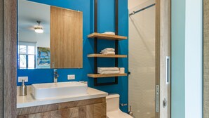 Een moderne badkamer met een houten wastafelmeubel, een witte wastafel en inbouwkasten voor handdoeken.