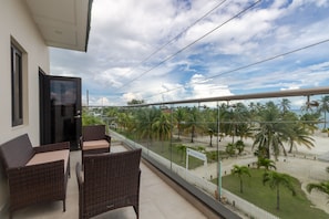 Enjoy the serene ocean views from this balcony, featuring wicker furniture and a glass railing.