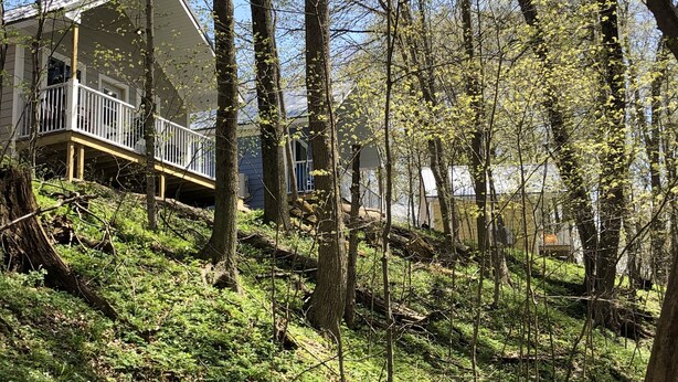 A house with a balcony on a hillside surrounded by trees.