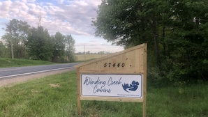 A wooden signboard with the text "Winding Creek Cabins" and a website address.