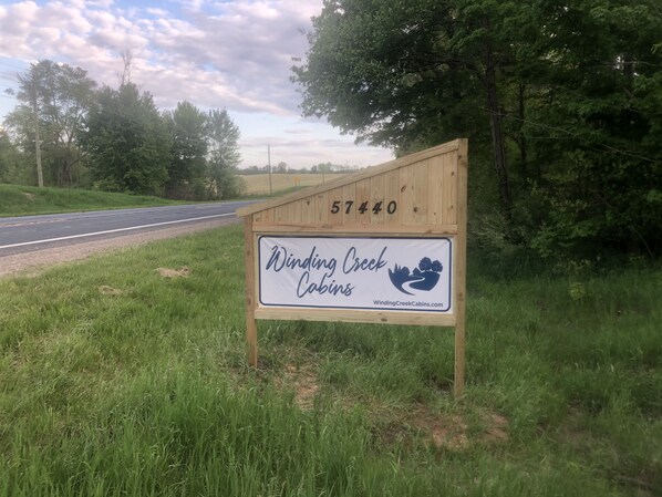 A wooden signboard with the text "Winding Creek Cabins" and a website address.