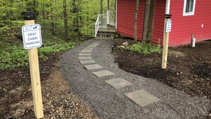 A gravel path leading to a red cabin with a white railing and steps.