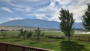 A view of a grassy field with a wooden fence and a mountain in the background. - Spacious Farm House with Stunning Mountain Views (Joseph)
