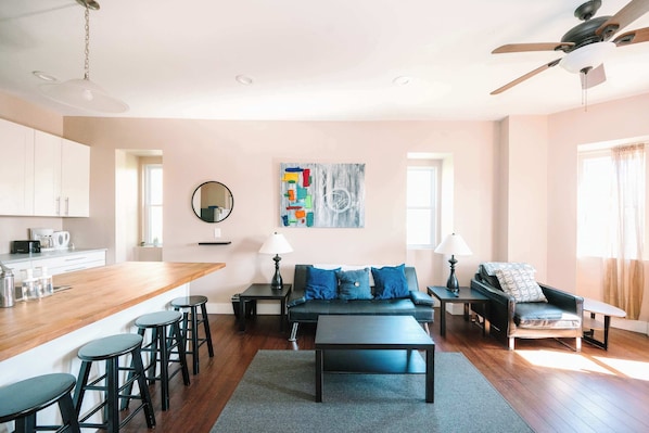 A modern living room with a sofa, coffee table, and bar stools.