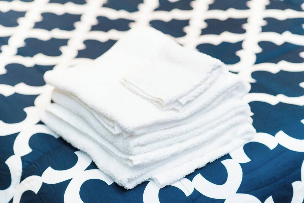 A stack of white towels on a patterned bedspread.