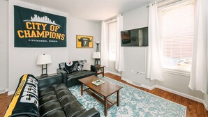 Ein Wohnzimmer mit einer Couch, einem Couchtisch und einem großen gerahmten Sportposter.