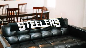 Eine schwarze Ledersofa mit einem Kissen, auf dem 'STEELERS' in weißen Buchstaben steht.