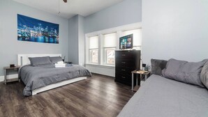 Een slaapkamer met een bed, een dressoir, een televisie en een raam.