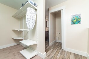 A room with a closet, a door leading to another room, and a painting on the wall.