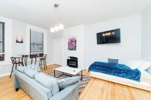 A modern living room with a sofa, coffee table, TV, and a fireplace.