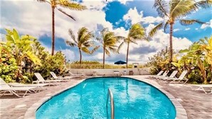 A swimming pool with lounge chairs and palm trees.