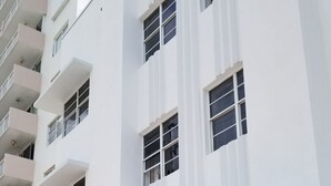 A multi-story building with a white facade, numbered 335, featuring a glass entrance and a small outdoor seating area.