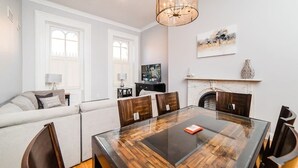 A dining area with a glass-top table, wooden chairs, a chandelier, a fireplace, and a sofa with cushions. - Outdoor Space - Parking - 1st Floor - Walkable (Pittsburgh)