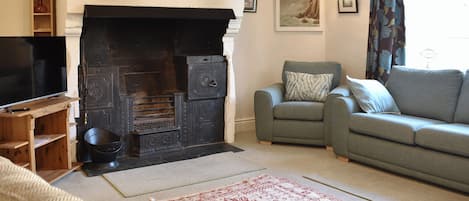 A living room with a fireplace, a sofa, a television, and a patterned rug.
