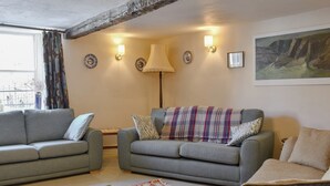 Ein Wohnzimmer mit zwei grauen Sofas, einem gemusterten Teppich und einem Gemälde an der Wand.
