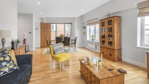 A spacious living room with a wooden coffee table, a yellow armchair, and a dark sofa. - Eleven Popeshead - 2 bed, 2 bath central apartment (York)
