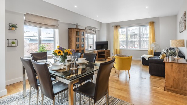 A modern living room with a dining area, wooden flooring, and a TV. - Eleven Popeshead - 2 bed, 2 bath central apartment (York)