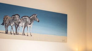 A hotel room with a bed, floral pillows, a nightstand with a lamp, and a painting of zebras on the wall. - Downshire Haven (Holywood)