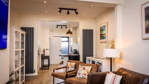 A modern living room with a leather sofa, a brown armchair, and a glass cabinet. - Downshire Haven (Holywood)