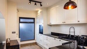 A modern kitchen with white cabinets, a black countertop, and a coffee machine. - Downshire Haven (Holywood)