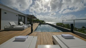 Un área de piscina en la azotea con sillones de descanso y vistas al mar.