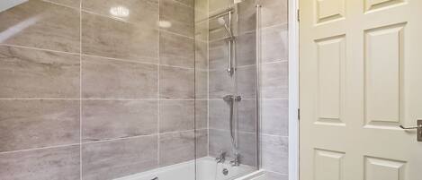 Une salle de bain avec une baignoire, une douche et une porte.