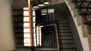 A staircase with a wooden handrail and black metal balusters, leading to a landing with a patterned door. - EL Colonial Hotel Open Bar Adults Only (San Juan)