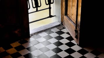 A room with a checkered floor, a wooden door, and a barred window.